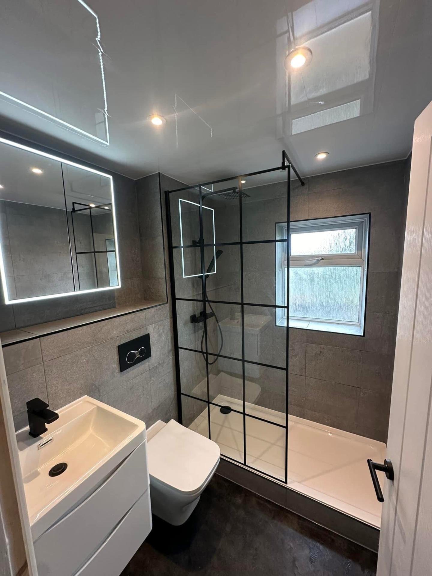 Modern grey bathroom with black framed crittall shower screen and LED mirror